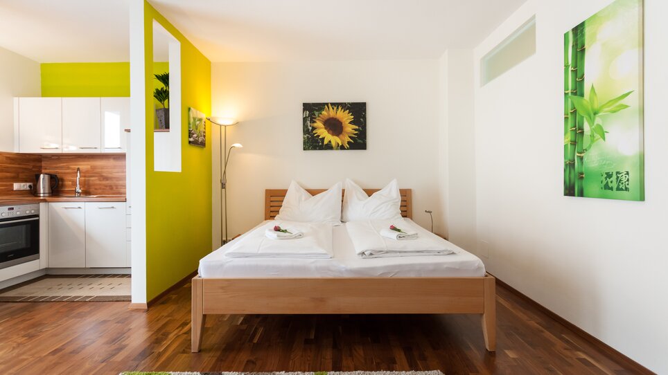 Cozy bedroom with cooking area, wooden floor, and plant motifs. | © R. Kaiser