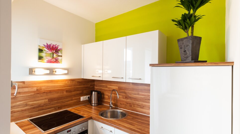 Compact kitchen with wooden surfaces, white cabinets, and green accent. | © R. Kaiser
