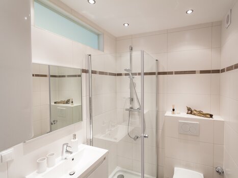 Un bagno moderno con doccia, specchio e dettagli eleganti. | © R. Kaiser