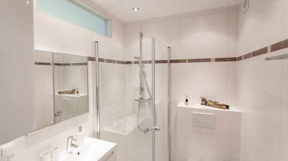 A modern bathroom featuring a shower, mirror, and elegant details. | © R. Kaiser