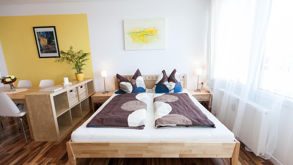 Cozy bedroom featuring a double bed, stylish decor, and a dining table. | © R. Kaiser