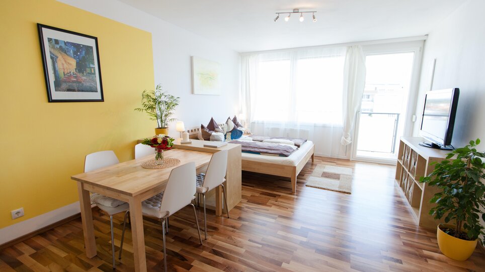 Cozy, sunlit room featuring a bed and dining table. | © R. Kaiser