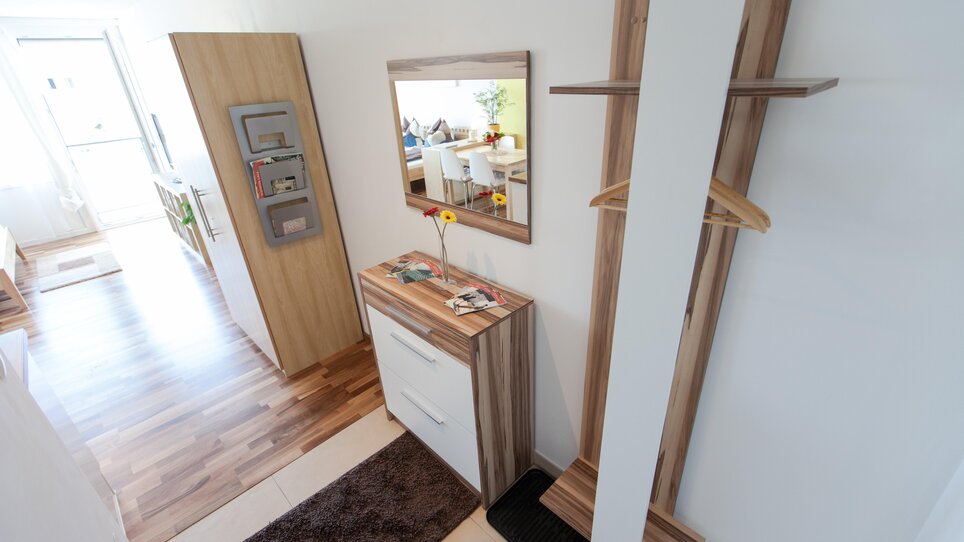 Bright hallway with wooden details, mirror, and storage. | © R. Kaiser