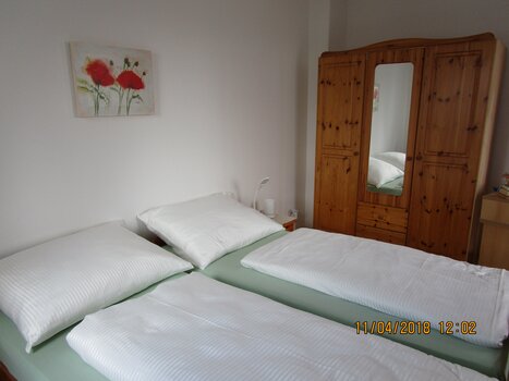 Sleeping area with bed and a wooden wardrobe. | © Appartement Anne-Marie