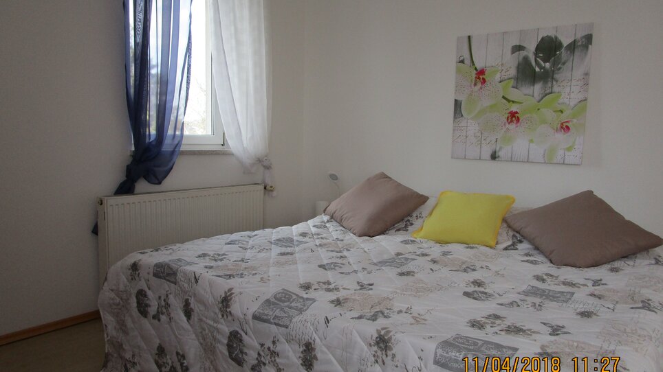 Camera con letto matrimoniale e quadro floreale sulla parete. | © Appartement Anne-Marie