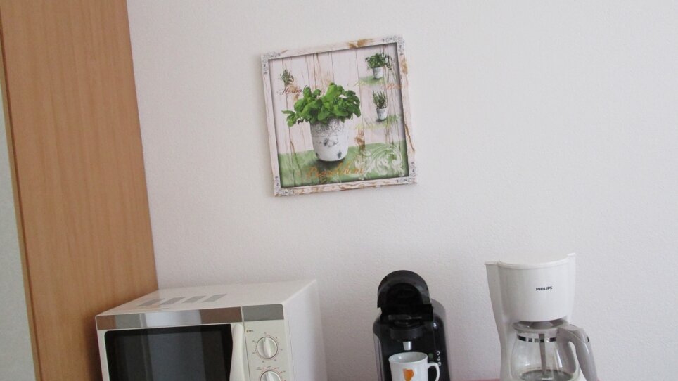 Area della cucina con microonde, macchina da caffè e decorazione. | © Appartement Anne-Marie