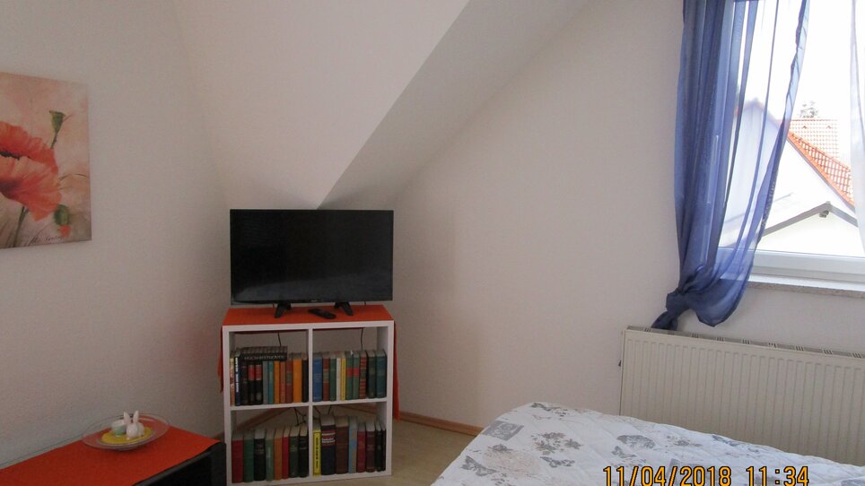 Camera accogliente con TV e libreria. | © Appartement Anne-Marie