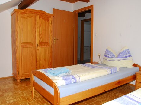 Cozy room with a bed, wardrobe, and table. | © Appartement Rupp