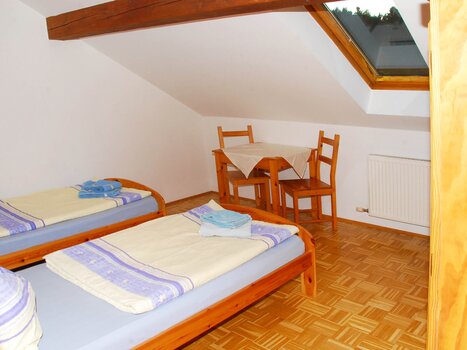 Simple room with two beds, a table, and chairs. | © Appartement Rupp