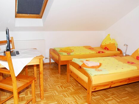 Bright, simply furnished room with two beds and a table. | © Appartement Rupp