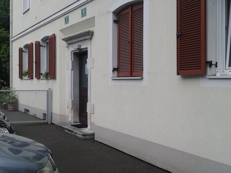 Der Eingang zu einem Wohngebäude mit roten Fensterläden | © Appartement St. Leonhard