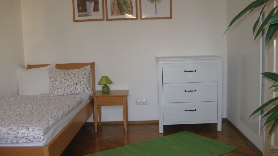Helles Zimmer mit Bett und Kommode. | © Appartement St. Leonhard