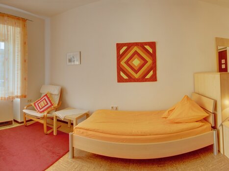 Cozy room featuring a bed and an armchair. | © App Alpha