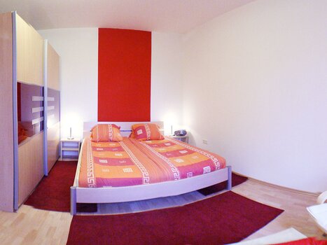 Bright bedroom featuring a double bed, wardrobe, and carpet. | © App Alpha