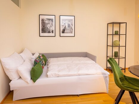 Cozy bedroom with sofa and pictures. | © Appartements Kalvarienberg