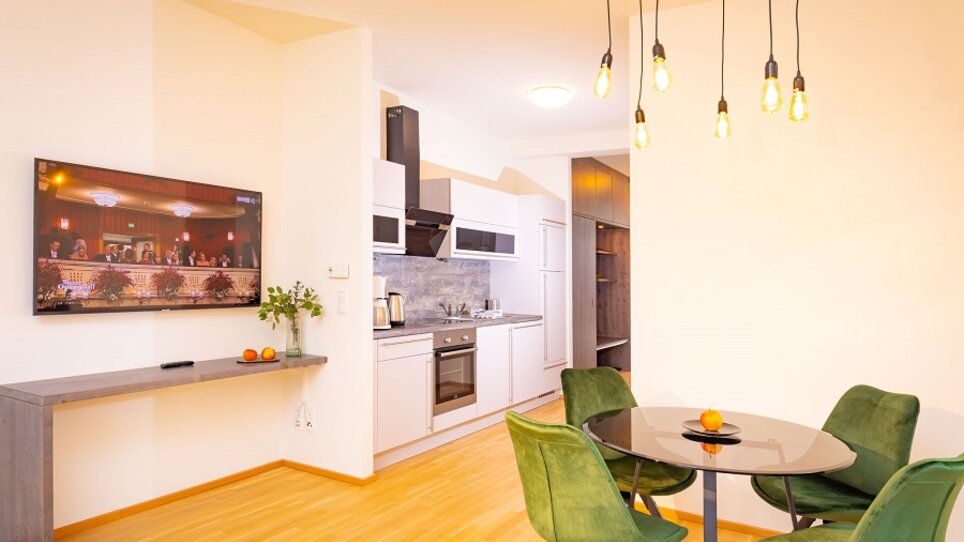 Helle Küche mit Esstisch und TV.