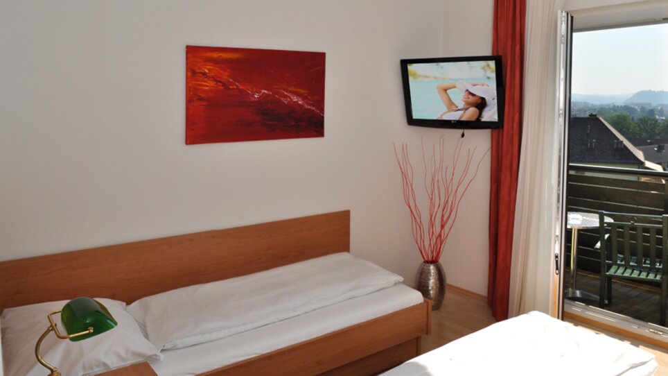Una camera moderna con due letti, TV e balcone a Graz. | © Steinbichler