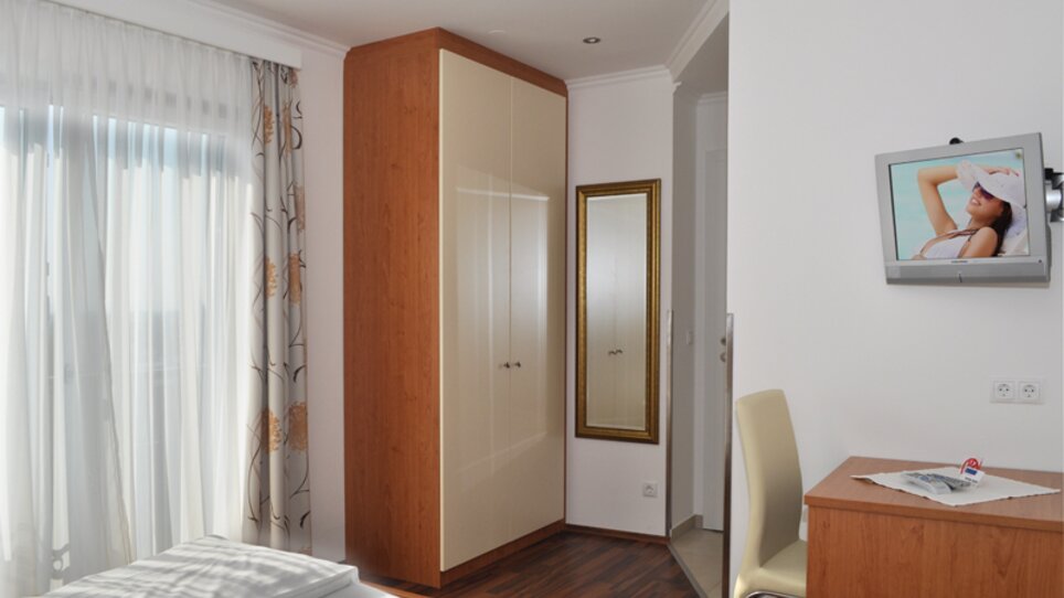 Stanza luminosa con finestra, armadio, un specchio e TV. | © Steinbichler