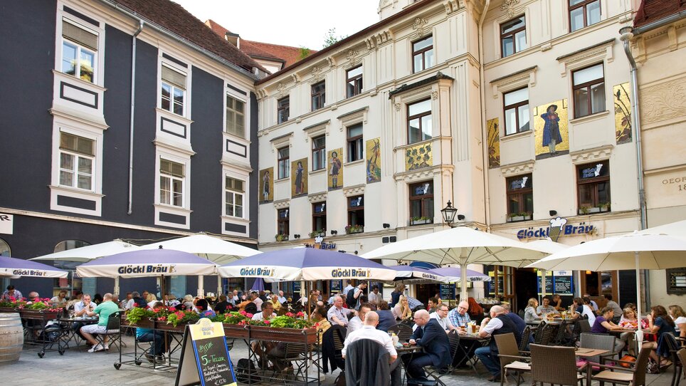 Vista esterna delgli appartamenti al GLockenspielplatz con clienti all'aperto. | © Grossauer Tourismus