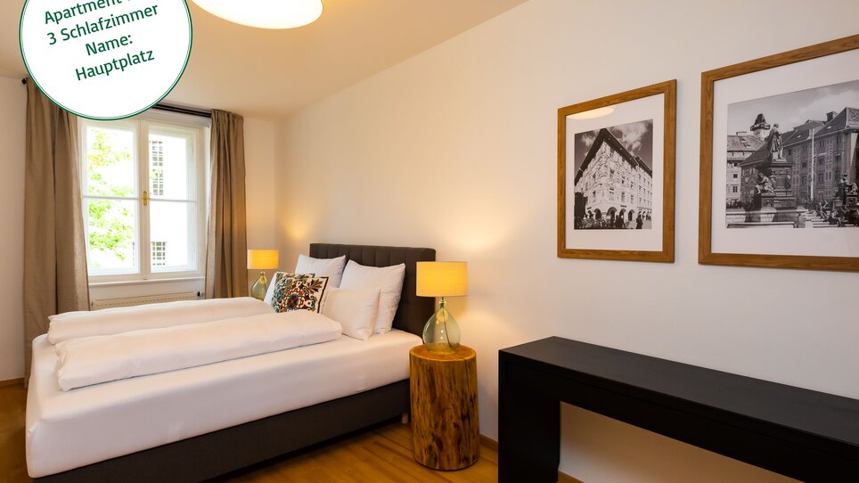 camera da letto arredata con letto matrimoniale, lampade moderne e quadri alle pareti