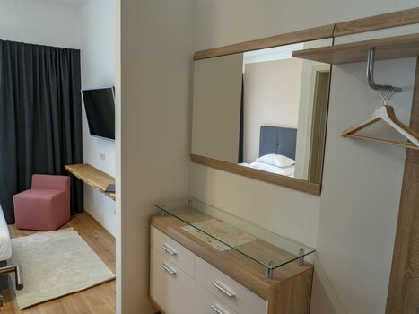 Einblick in ein Zimmer im Gästehaus Mosshammer mit TV, Spiegel und einem Stuhl. | © Mosshammer