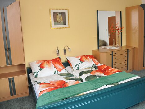 Una camera da letto nella Gartenvilla Irene con scaffali in legno e biancheria colorata. | © Gartenvilla Irene