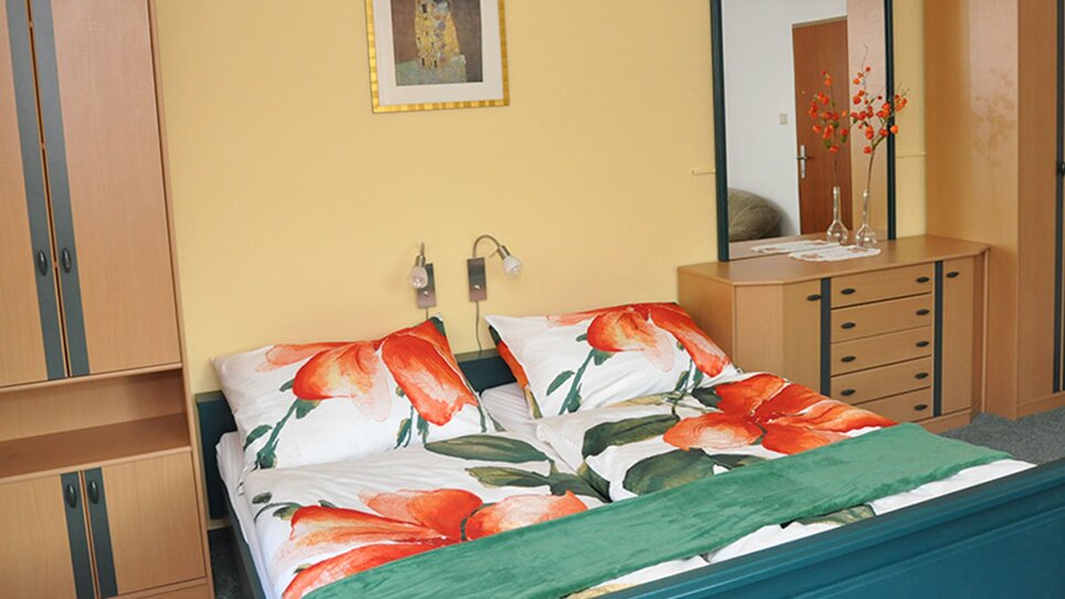 Una camera da letto nella Gartenvilla Irene con scaffali in legno e biancheria colorata. | © Gartenvilla Irene