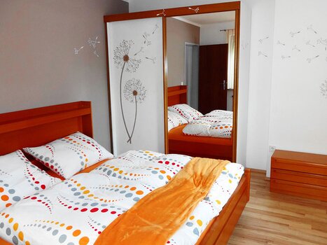 Vista di una camera da letto con letti in legno e biancheria a fantasia. | © Gartenvilla Irene