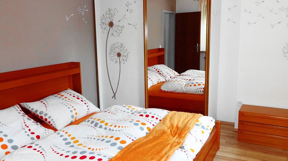 Vista di una camera da letto con letti in legno e biancheria a fantasia. | © Gartenvilla Irene