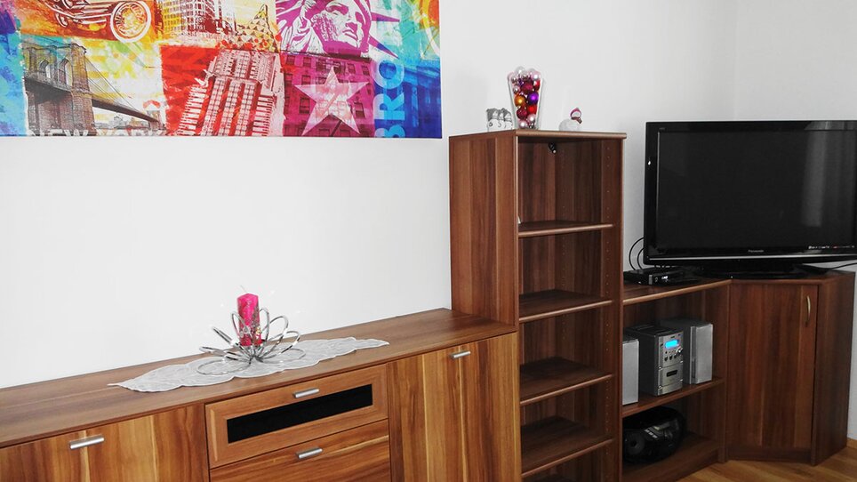 Un interno con mensole in legno e una TV nella Gartenvilla Irene. | © Gartenvilla Irene