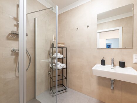 Bathroom with shower, sink, and shelves. | © Grazora Living