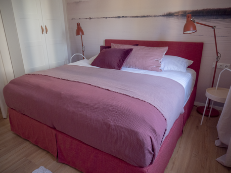 Un letto con cuscini viola e bianchi in una camera da letto moderna. | © GrazRentals