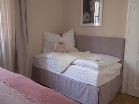 Un letto con cuscini e una coperta in una stanza luminosa. | © GrazRentals