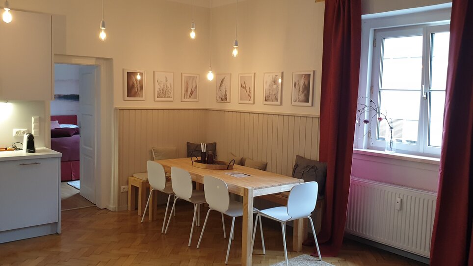 Una vista di una sala da pranzo con tavolo, sedie e quadri sulla parete. | © GrazRentals