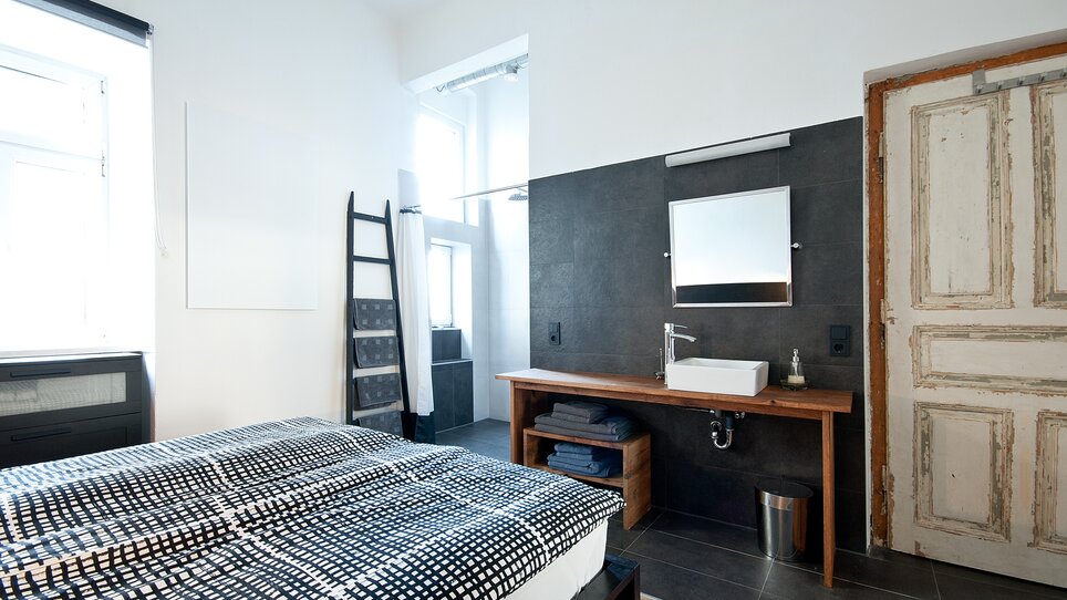 Interno di una stanza con un letto e un lavandino. | © Grocholl