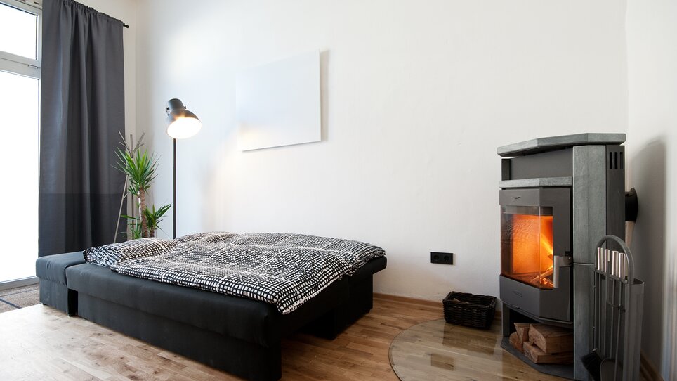 Una camera da letto con un letto, un caminetto e piante. | © Grocholl