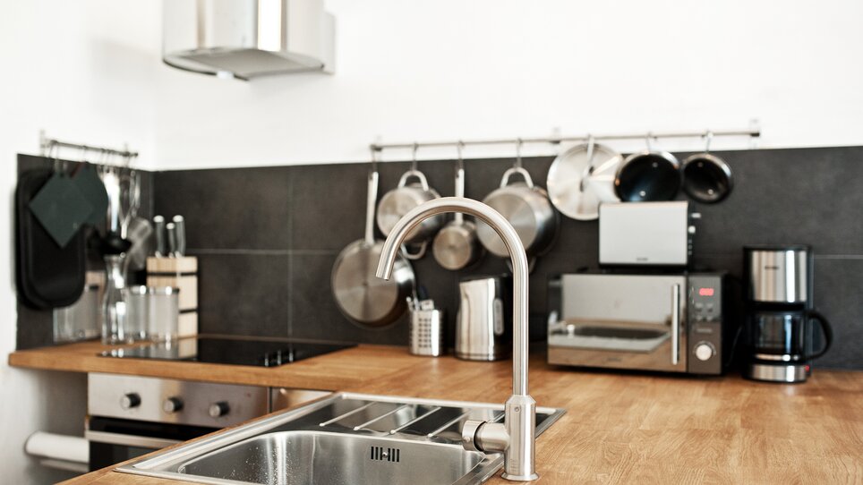 Una cucina moderna con lavello in acciaio inossidabile, elettrodomestici e pentole. | © Grocholl