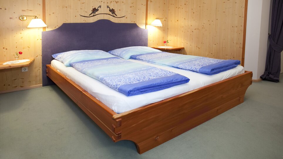 Camera da letto con due letti e rivestimento in legno. | © Haus Anna – Apartments im Garten