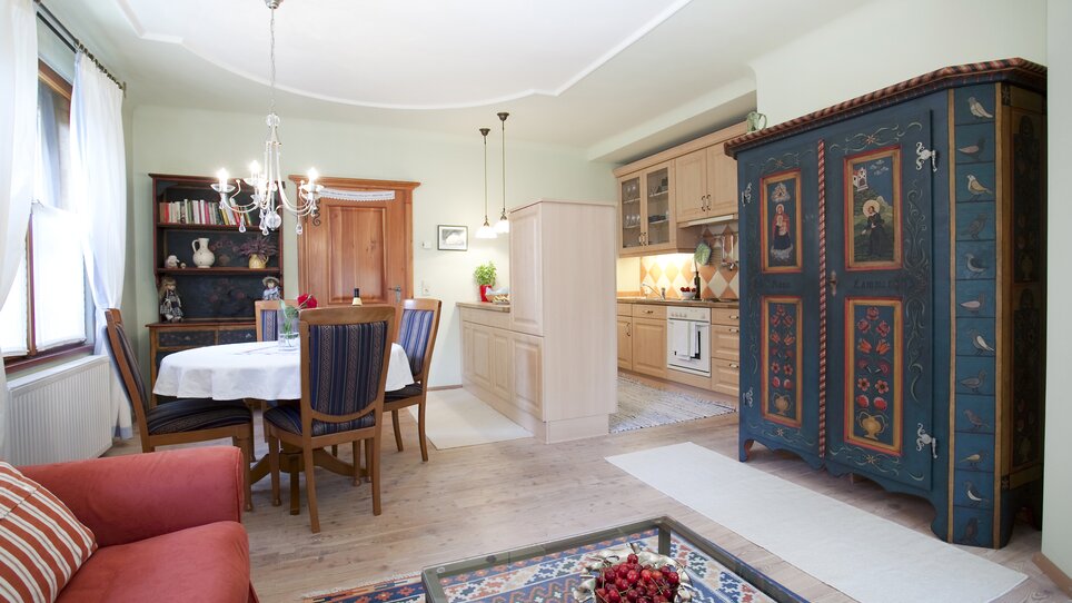 Area pranzo accogliente con angolo cottura e armadio antico. | © Haus Anna – Apartments im Garten