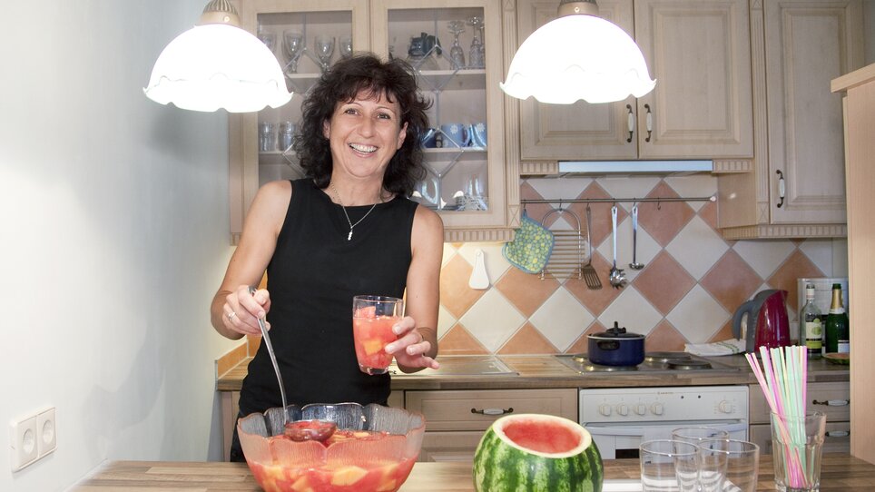 Una donna serve sangria alla frutta in una cucina moderna. | © Haus Anna – Apartments im Garten