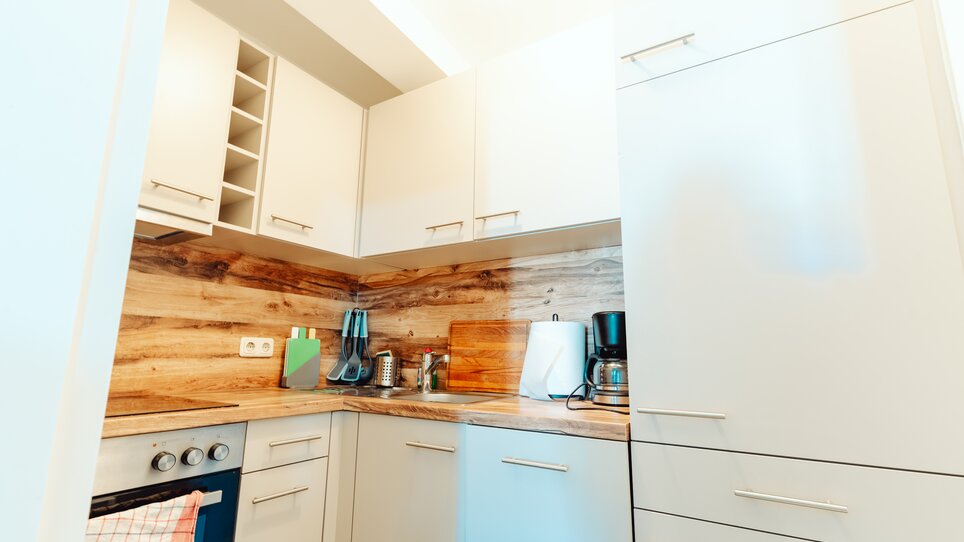 Eine moderne Küche mit Holzverkleidung, Geräten und Stauraum. | © Lilians Apartments