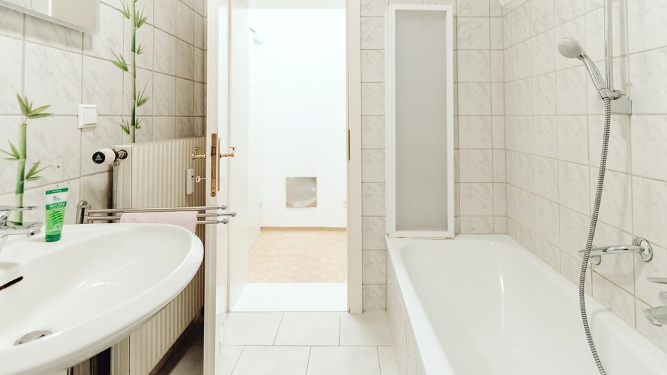 Ein modernes Badezimmer mit einer Badewanne, Waschbecken und einer Tür zu einem weiteren Raum. | © Lilians Apartments