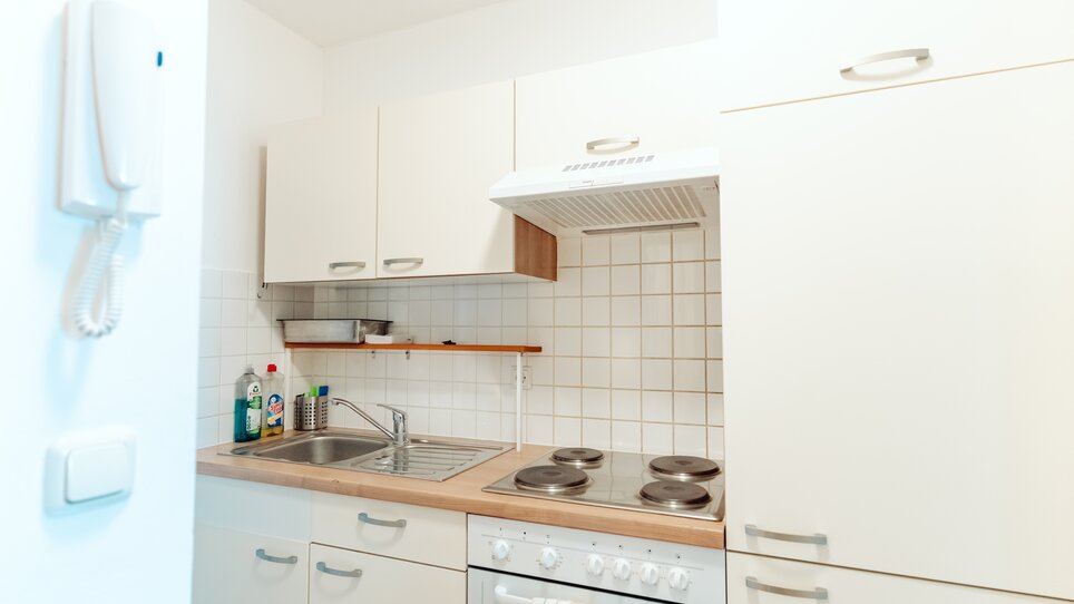 Kompakte Küche mit Spüle, Herd und Dunstabzugshaube. | © Lilians Apartments