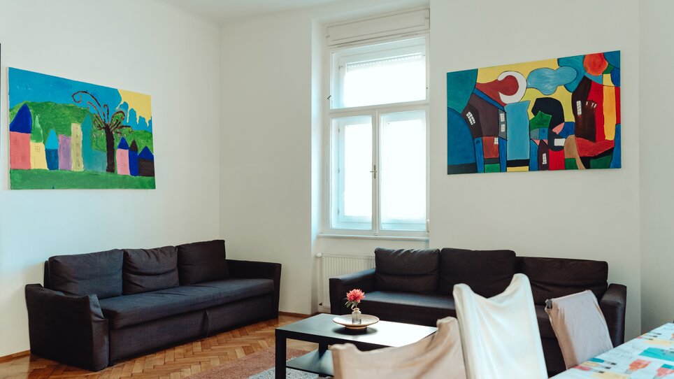 Eine stilvolle Sitzgruppe mit bunten Kunstwerken an der Wand. | © Lilians Apartments