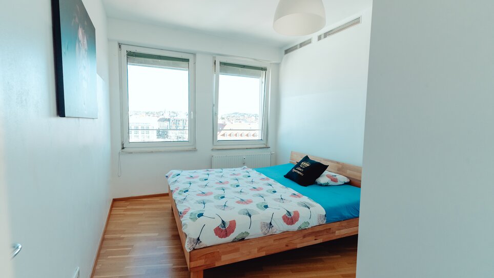 Gemütliches Schlafzimmer mit Holzfußboden und Fenstern. | © Lilians Apartments