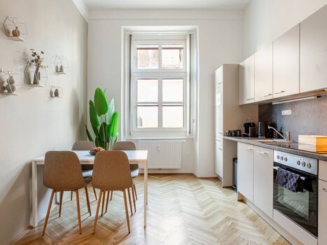 Bright kitchen featuring a table, chairs, and a green plant. | © HERO HOMES Design Apartments