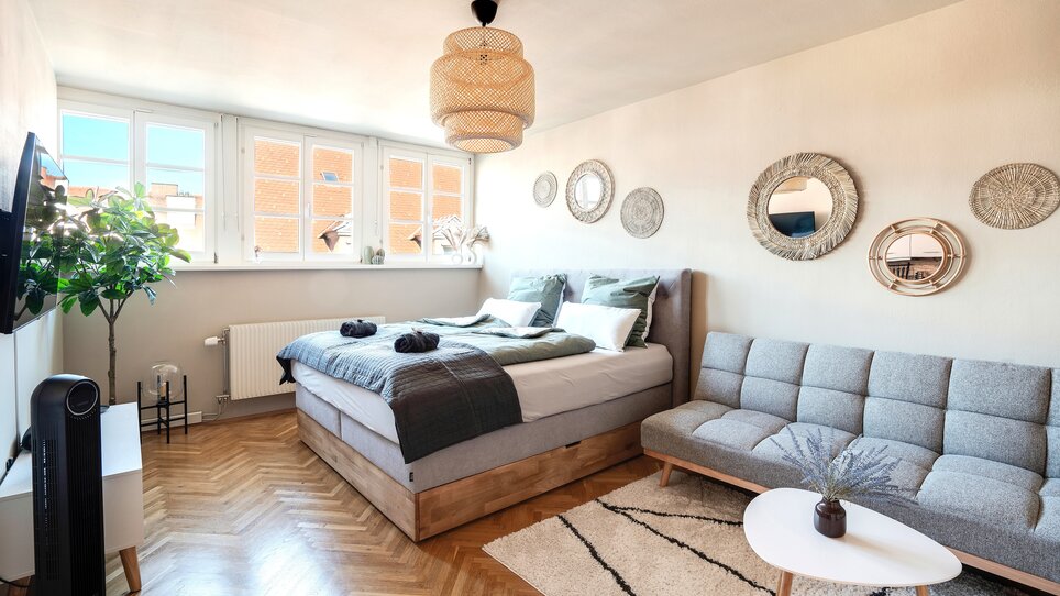 Gemütliches Schlafzimmer mit Doppelbett und Couch in neutralen Farben. | © HERO HOMES Design Apartments