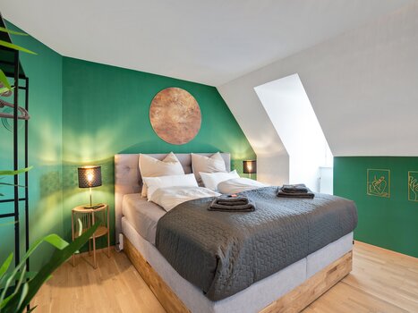 Modern bedroom with double bed and green walls. | © HERO HOMES Design Apartments