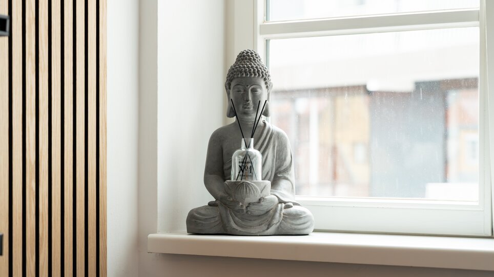 Graue Buddhafigur auf der Fensterbank. | © HERO HOMES Design Apartments
