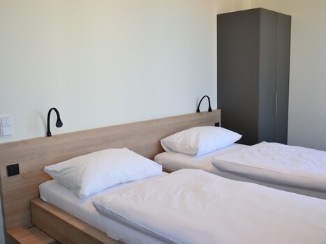 Two single beds in a bright room with a wardrobe. | © Tomo-Tec Immo GmbH